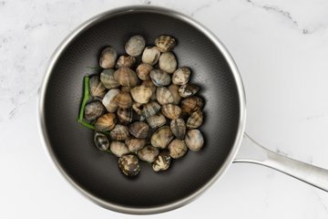 Venusmuscheln mit Knoblauch und Petersilie in der Pfanne